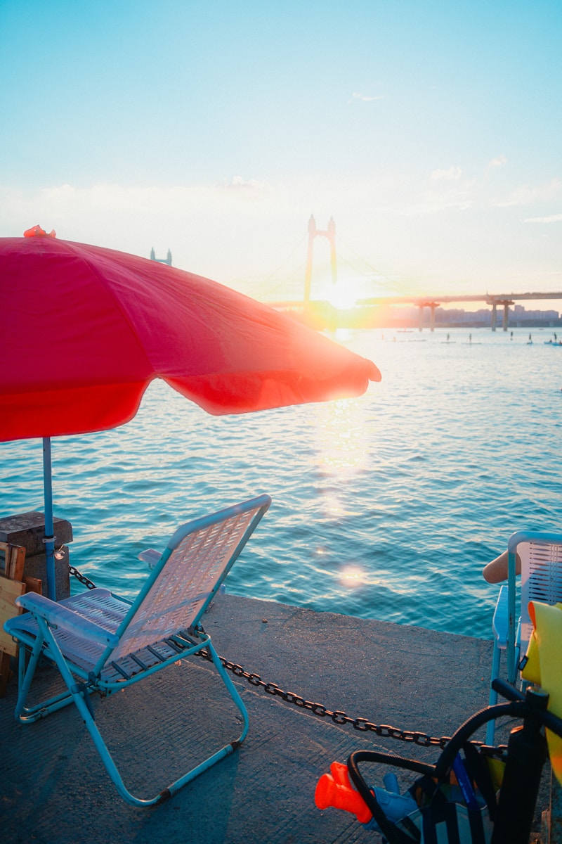 Beach chairs and umbrella by the ocean at sunset.