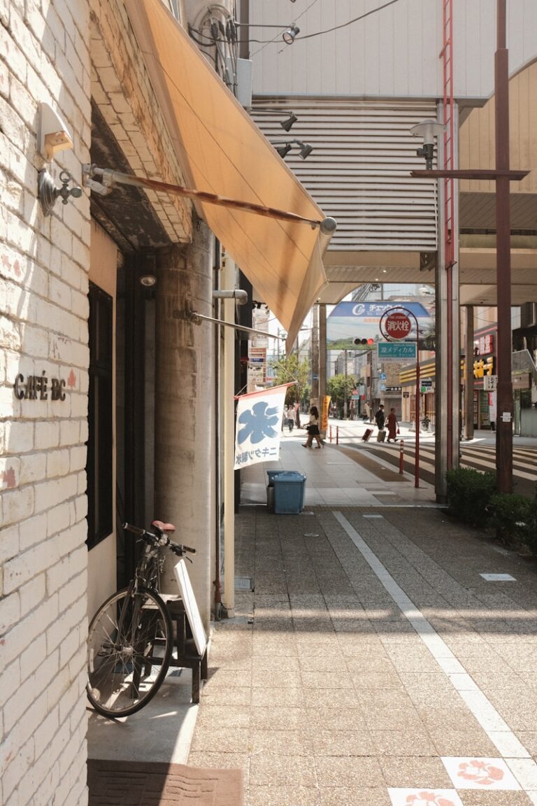 Bicycle parked outside a cafe on a sunny street.