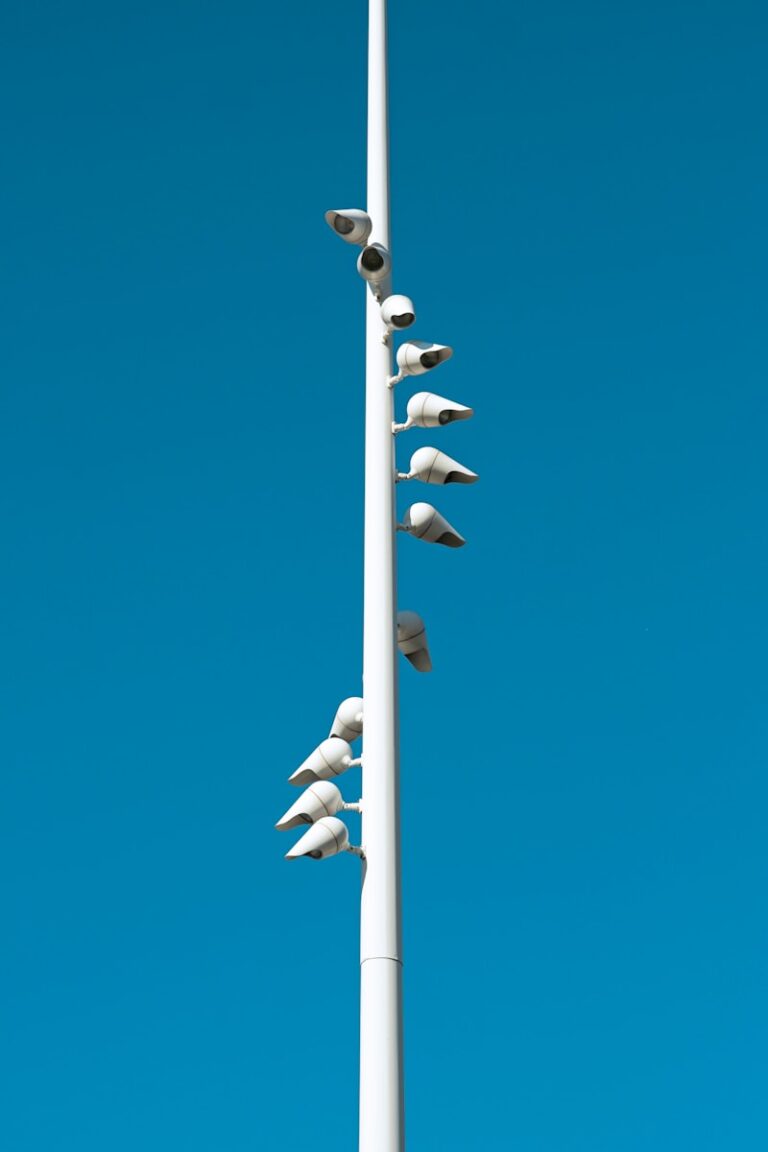 White pole with security cameras against blue sky