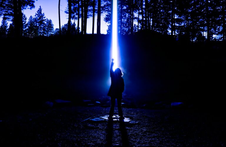 Person reaching for a bright blue light beam.