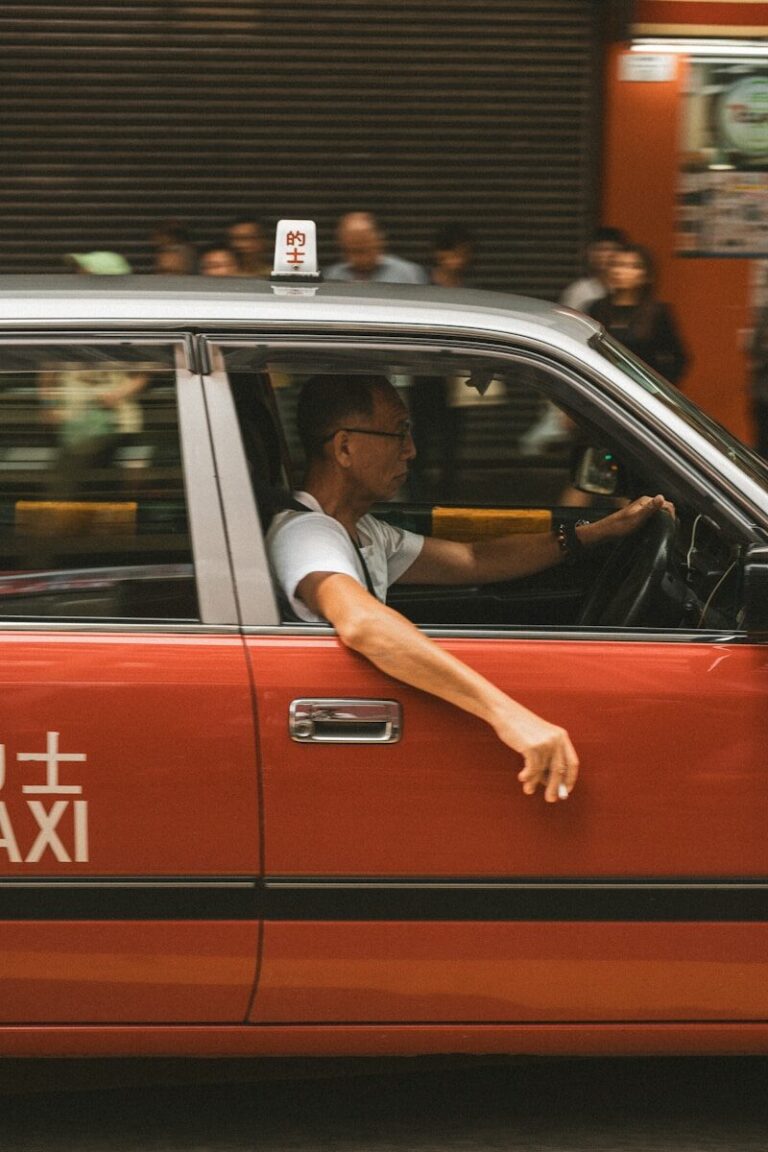 Man driving a red taxi in a city